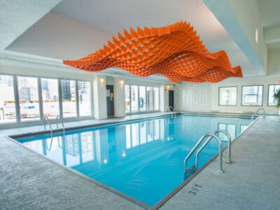 orange-acoustic-ceiling-design-above-pool-water orange acoustic ceiling design suspended above filled swimming pool