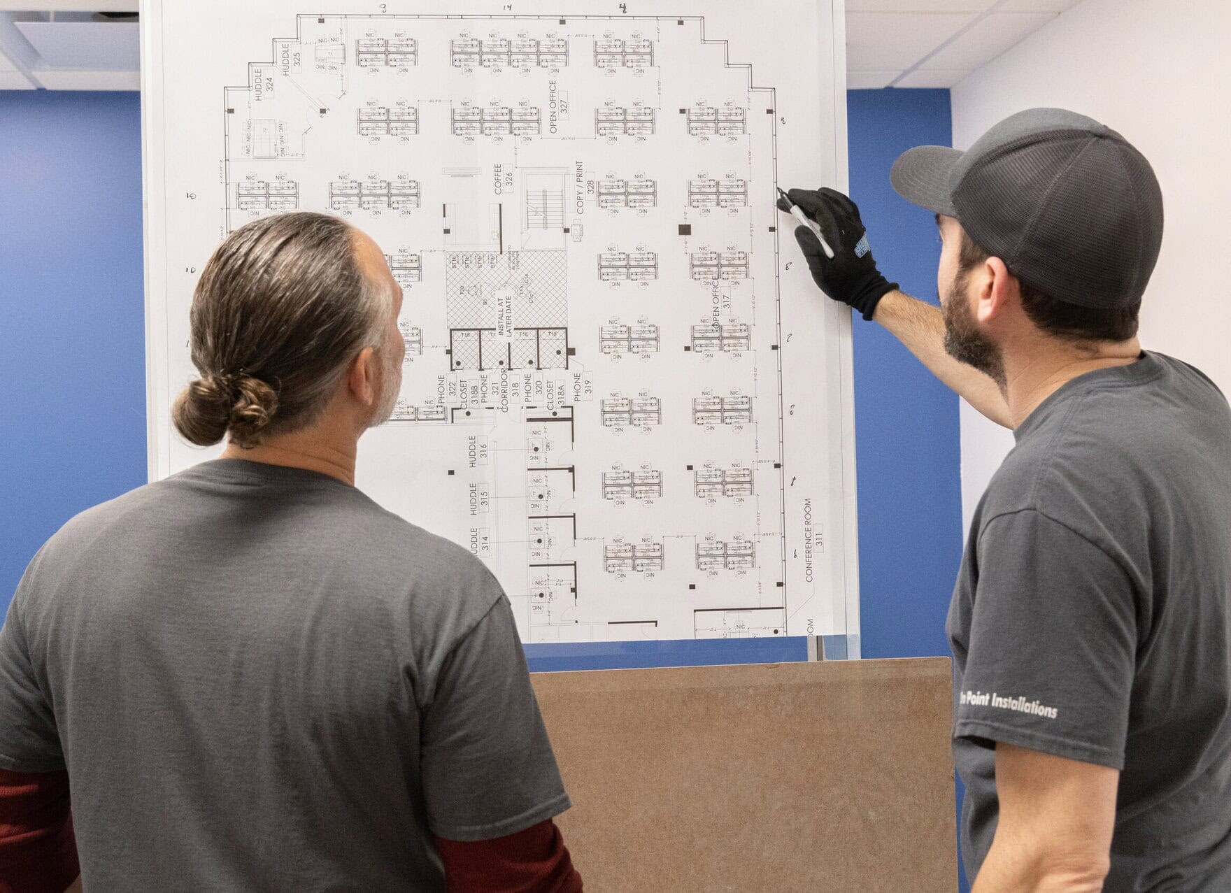 On Point Installations' Team Members communicating while looking at a project schematic 